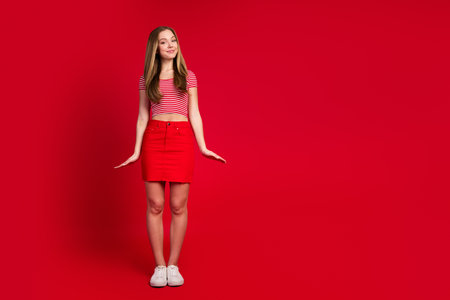 Full length photo of good mood sweet lady dressed striped top mini skirt empty space isolated red color backgroundの写真素材