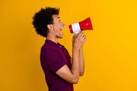 Profile side photo of cheerful excited guy wear violet trendy clothes announce news looking empty space isolated on yellow color backgroundの写真素材