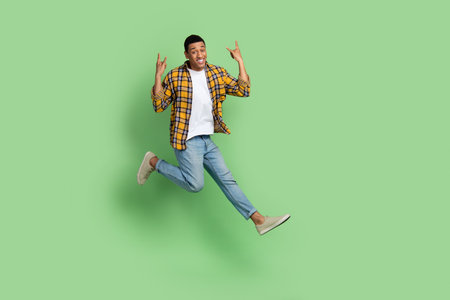 Full size portrait of carefree active sporty guy jump demonstrate heave metal symbol empty space...