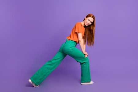 Full body photo of young lady in green jeans posing stretching right left to test quality new...