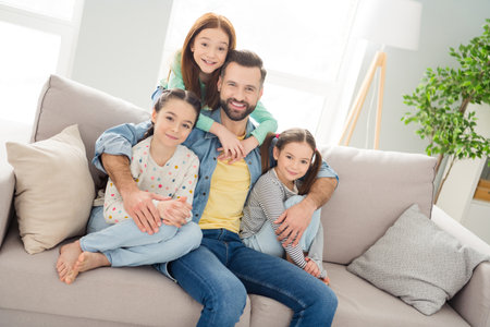 Photo of four persons sit on couch guy hugging girls toothy smile enjoy free time weekend hone...