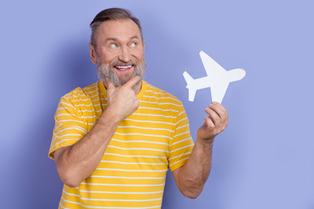 Photo of minded retired man dressed striped t-shirt hold paper plane planing vacation look empty...