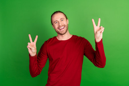 Portrait of good mood cheerful guy with long hairstyle wear red sweatshirt showing v-sign say hi...