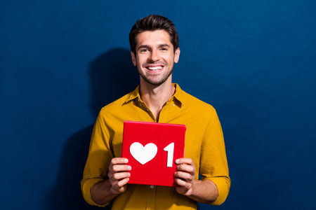Photo portrait of attractive young man hold heart icon influencer wear trendy yellow clothes...