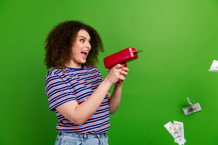 Profile portrait of impressed crazy girl hold money gun look shoot dollar bills empty space isolated...