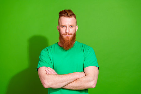 Photo of serious confident man dressed t-shirt arms crossed empty space isolated green color backgroundの写真素材