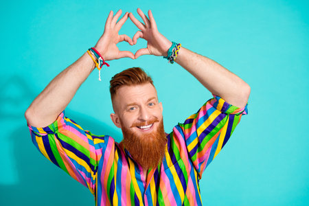 Portrait of red hair bearded boyfriend in elegant shirt show love gesture heart as feelings indicator isolated on cyan color backgroundの写真素材