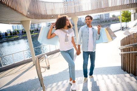 Full body size photo of happy couple shopping day family together holding hands walking on fresh air near supermarket with packagesの写真素材