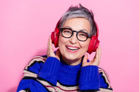 Photo portrait of pretty retired female headphones listen music wear trendy blue striped outfit isolated on pink color backgroundの写真素材