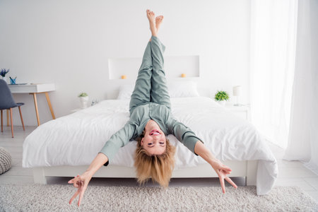 Full body length photo lying body down legs up lady in pajama loves her new comfortable bed showing...