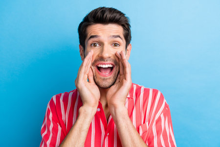 Photo of ecstatic overjoyed man with bristle dressed striped shirt shout announcing big season sale isolated on blue color backgroundの写真素材