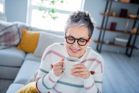 Photo of cheerful pretty lady wear striped pullover spectacles enjoying coffee aroma indoors room...