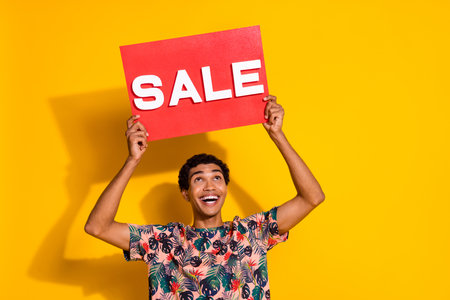 Photo of looking above head young promoter man in trendy t shirt holding red poster sale word...