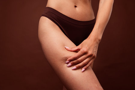 No retouch cropped photo of natural thin woman wear lingerie hand showing cellulite on hips isolated...