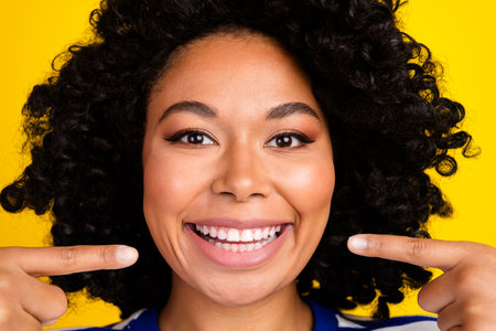 Close up portrait of cheerful lovely cute girl showing healthy white teeth veneers advertise...