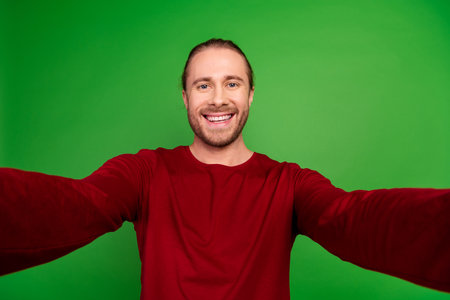 Portrait of toothy beaming handsome guy with long hairstyle wear red sweatshirt smile on selfie...
