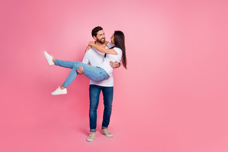 Full size photo of attractive young couple carry hold girlfriend wear trendy white outfit isolated on pink color backgroundの写真素材