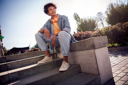 Photo of positive cheerful dreamy youngster with afro hairdo dressed jeans jacket in headphones...