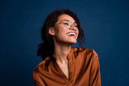 Photo of pretty shiny lady wear silk brown shirt spectacles laughing looking empty space isolated blue color backgroundの写真素材