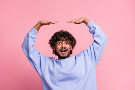 Photo of positive nice funny man wear stylish blue clothes arms hold empty space proposition novelty isolated on pink color backgroundの写真素材