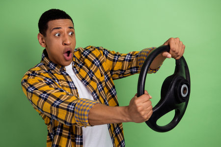 Photo of young nervous man wearing yellow checkered shirt has no drivers license holding steering...