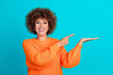 Photo of gorgeous satisfied woman wear trendy orange autumn clothes introduce news empty space isolated on blue color backgroundの写真素材
