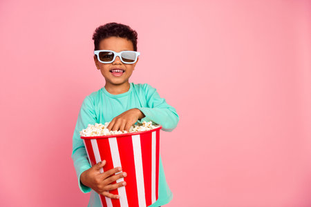 Photo portrait of charming small boy watch movie eat popcorn 3d glasses wear trendy aquamarine outfit isolated on pink color backgroundの写真素材