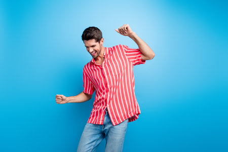 Photo of satisfied pleasant man with bristle trendy haircut dressed striped shirt dancing have fun isolated on blue color backgroundの写真素材