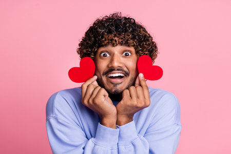 Photo of glad funky cheerful man wear trendy blue clothes showing red card have fun festive event isolated on pink color backgroundの写真素材