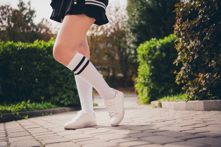 Cropped photo of girl legs dressed knees socks mini skirt white footwear walking school outdoors...