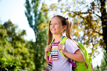 Photo of adorable cute little girl dressed tied jumper rucksack walking courses enjoy good weather outdoors urban city parkの写真素材