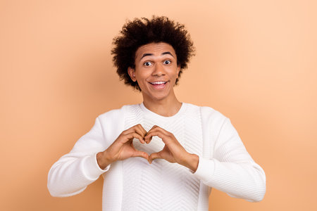 Photo of cheerful kind boyfriend wear trendy white jumper demonstrate heart sign affection isolated...