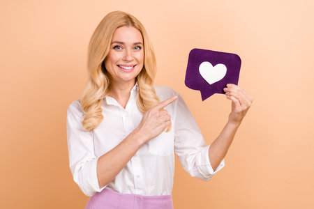 Photo of charming cheerful lady dressed white shirt pointing finger feedback card isolated beige...