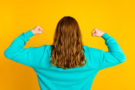 Rear behind portrait of confident person hands flexing biceps curly shiny hair isolated on yellow...