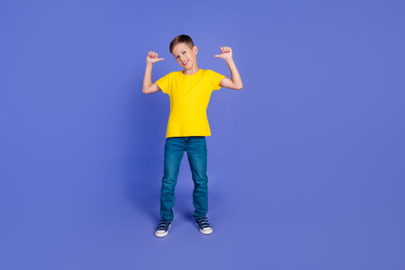 Photo of cute cheerful cute child boy wear stylish yellow clothes new collection isolated on purple color backgroundの写真素材