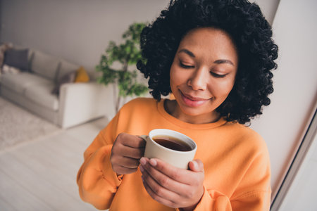 Photo portrait of lovely young lady drink coffee enjoy morning dressed casual orange clothes cozy...