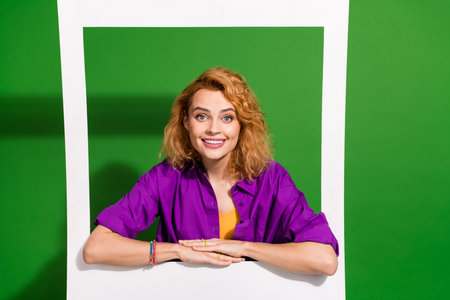 Photo portrait of lovely young lady lean on instant photo frame dressed stylish violet clothes isolated on green color backgroundの写真素材