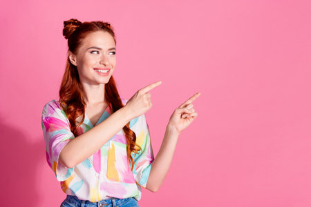 Photo of cheerful girl with redhair tails dressed colorful blouse look directing at sale empty space isolated on pink color backgroundの写真素材