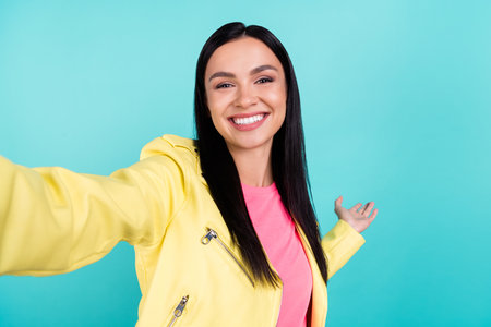 Photo of young lovely girl make selfie gesture hand empty space welcome friendly isolated over teal color backgroundの写真素材