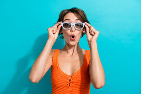 Photo of overjoyed stunned woman dressed knitwear singlet touch 3d glasses staring open mouth isolated on turquoise color backgroundの写真素材