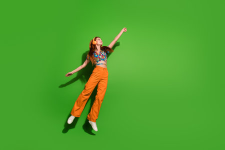 Full size photo of pretty young woman jump hand hold empty space wear top isolated on bright green color backgroundの写真素材