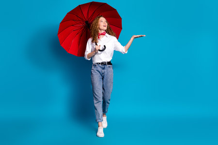 Photo portrait of nice young lady look hold empty space hold umbrella wear trendy white garment isolated on blue color backgroundの写真素材