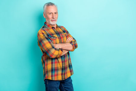 Photo of confident man pensioner dressed checkered shirt arms folded empty space isolated teal color backgroundの写真素材