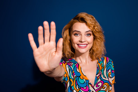 Portrait of cheerful lovely cute woman wear trendy clothes showing arm palm highfive isolated on dark blue color backgroundの写真素材