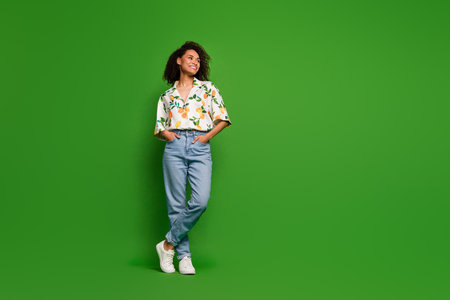 Full length photo of adorable pretty lady wear print shirt hands pockets looking empty space isolated green color backgroundの写真素材