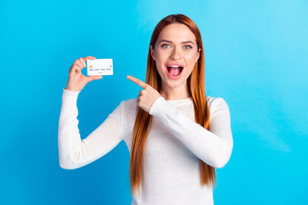 Photo portrait of attractive young woman hold point credit card amazed dressed stylish white clothes isolated on blue color backgroundの写真素材