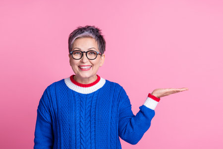 Photo of adorable lovely retired woman wear trendy blue clothes hold product offer empty space isolated on pink color backgroundの写真素材