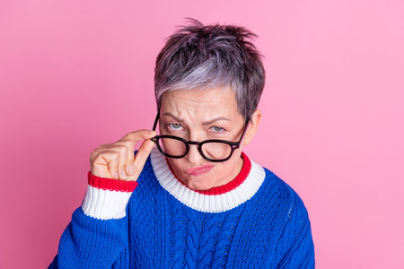 Photo of nice aged lady touch eyeglasses think wear blue sweater isolated on pink color backgroundの写真素材