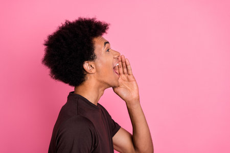 Side profile photo of young funny curly hair man in brown t shirt touch cheek announcement empty space isolated on pink color backgroundの写真素材