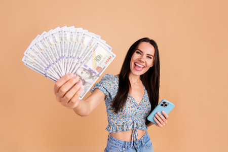 Photo of crazy cheerful woman wear blue trendy clothes showing cash lottery million isolated on beige color backgroundの写真素材
